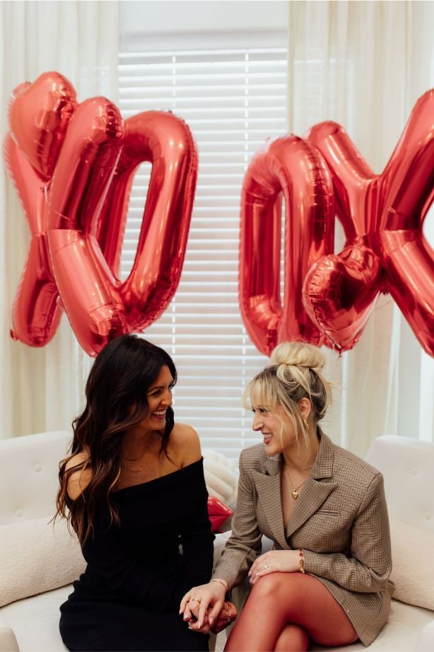 owners sitting on couch with red XO balloons